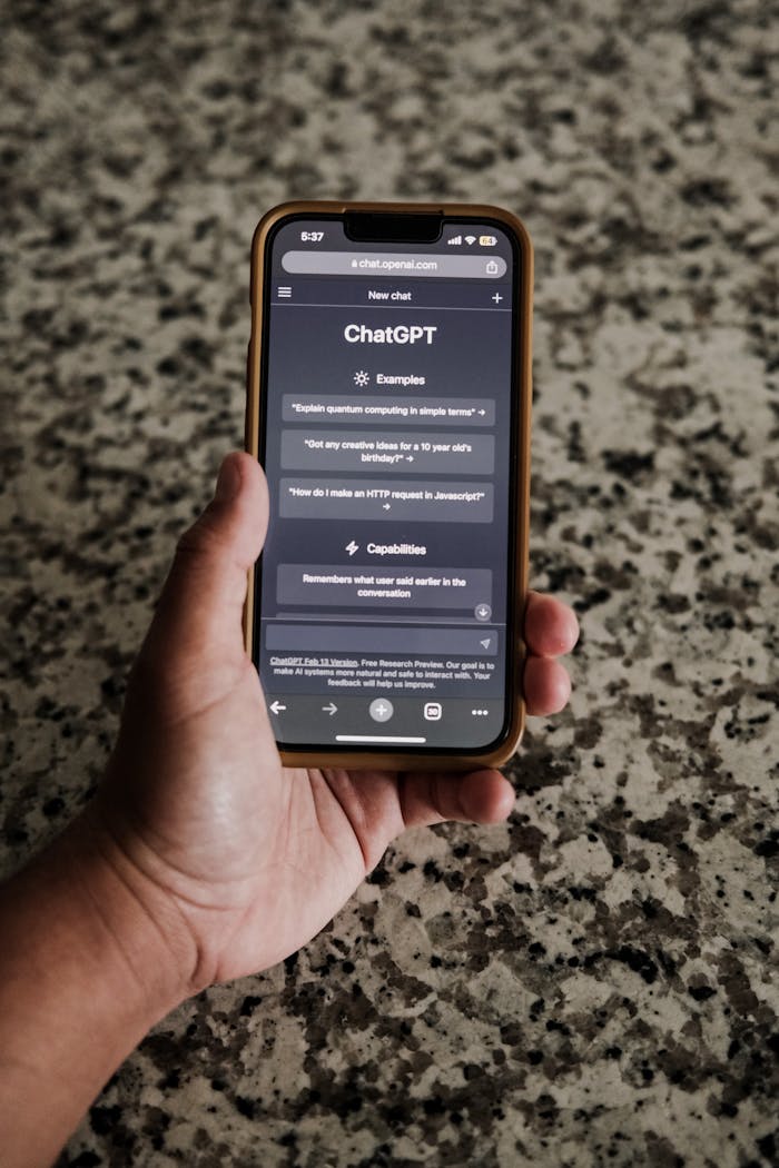 A close-up of a hand holding a smartphone with ChatGPT interface on display.